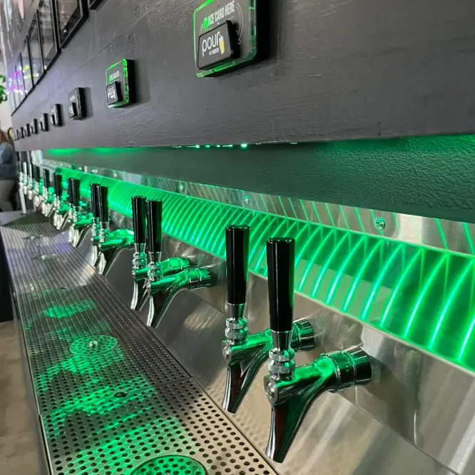The green-lit draft beer wall at Arcade 11
