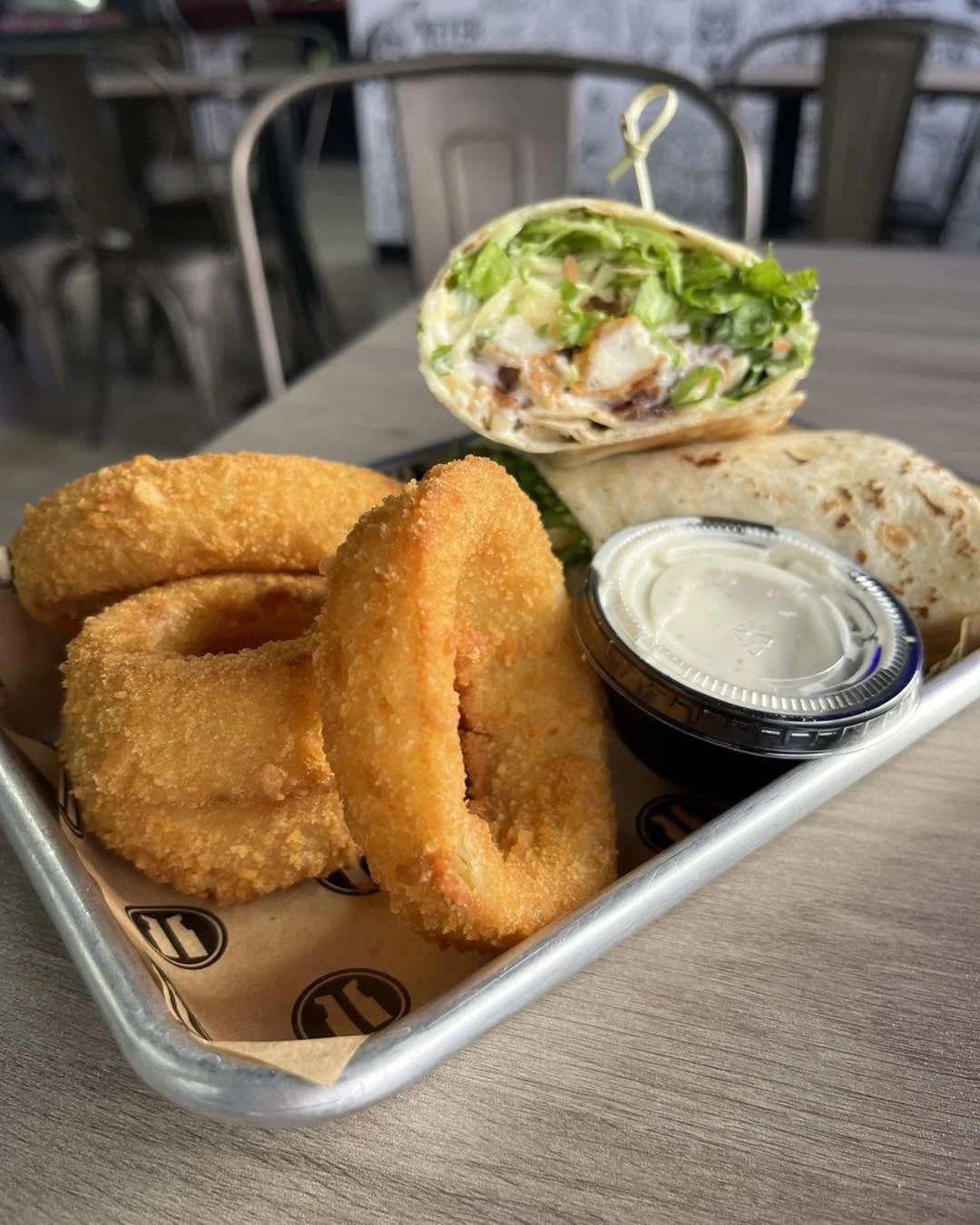 Cut wrap with fresh greens, golden onion rings and dip at Arcade 11